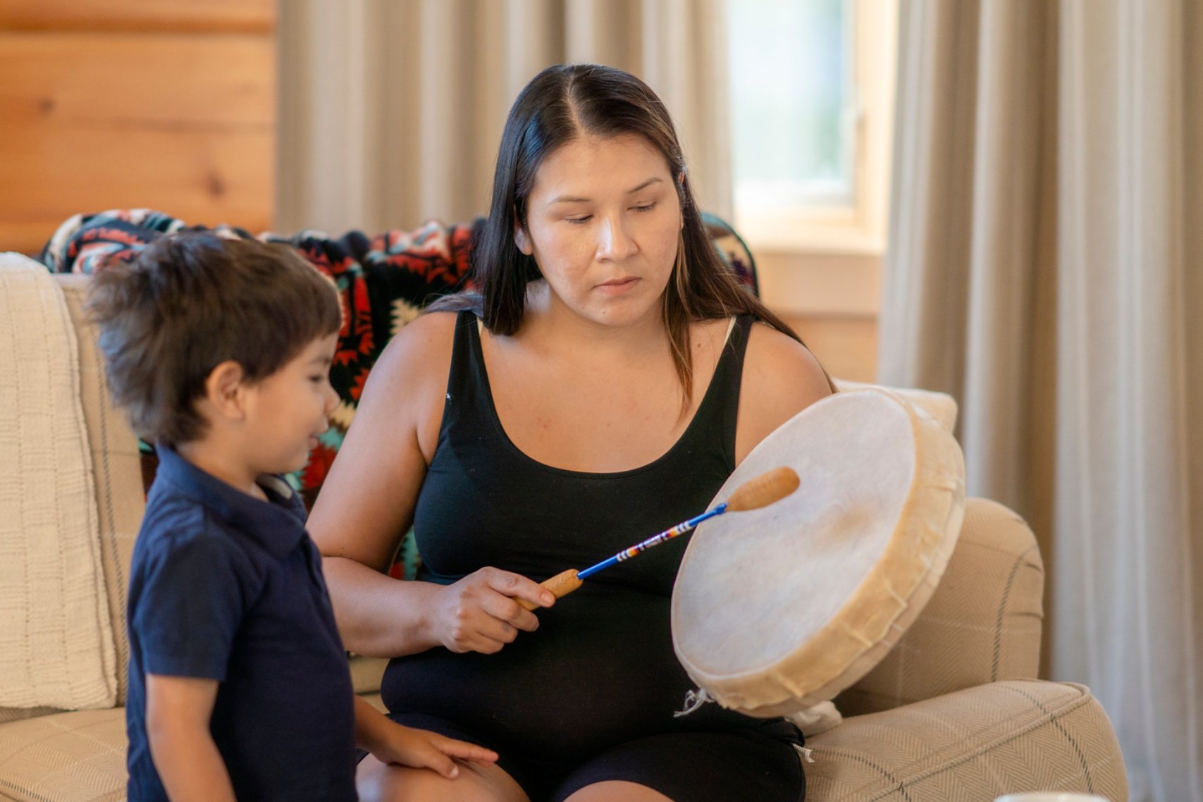 Indigenous mother playing the drums for her son at home