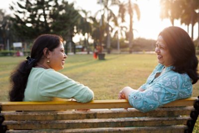 Two women talking while sitting on a bench