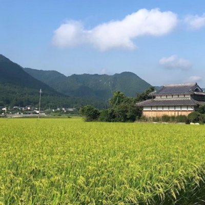 A picture of a house in a wide field and hills in the background