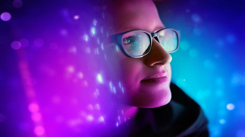 Woman with glasses with colorful projection behind and in front.