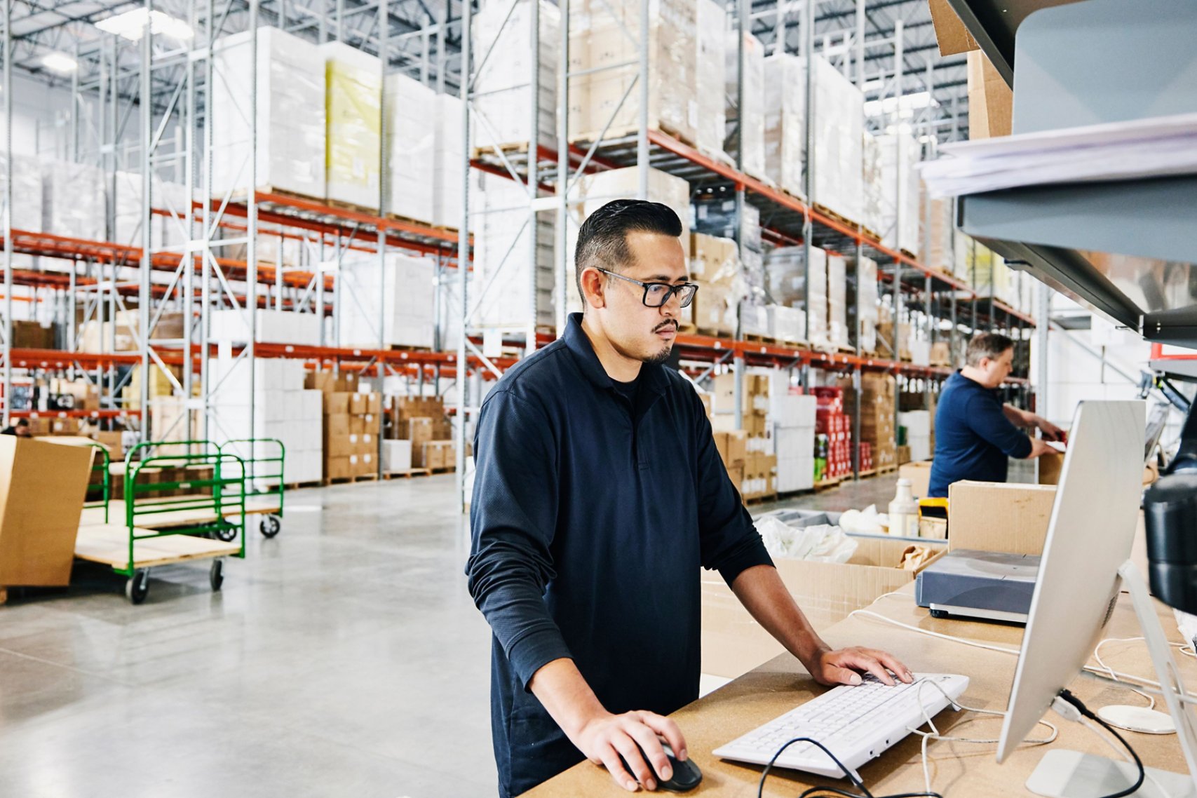 male warehouse worker checking orders at computer workstation in warehouse
