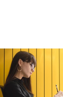 A woman wearing eyeglasses writing on a book