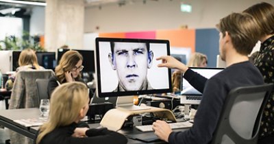 Three people pointing to a screen.