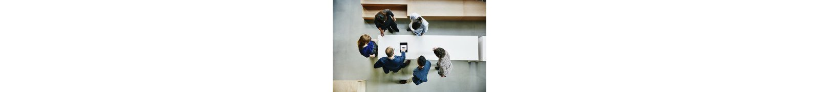 A group of people standing around looking an art on top of the table