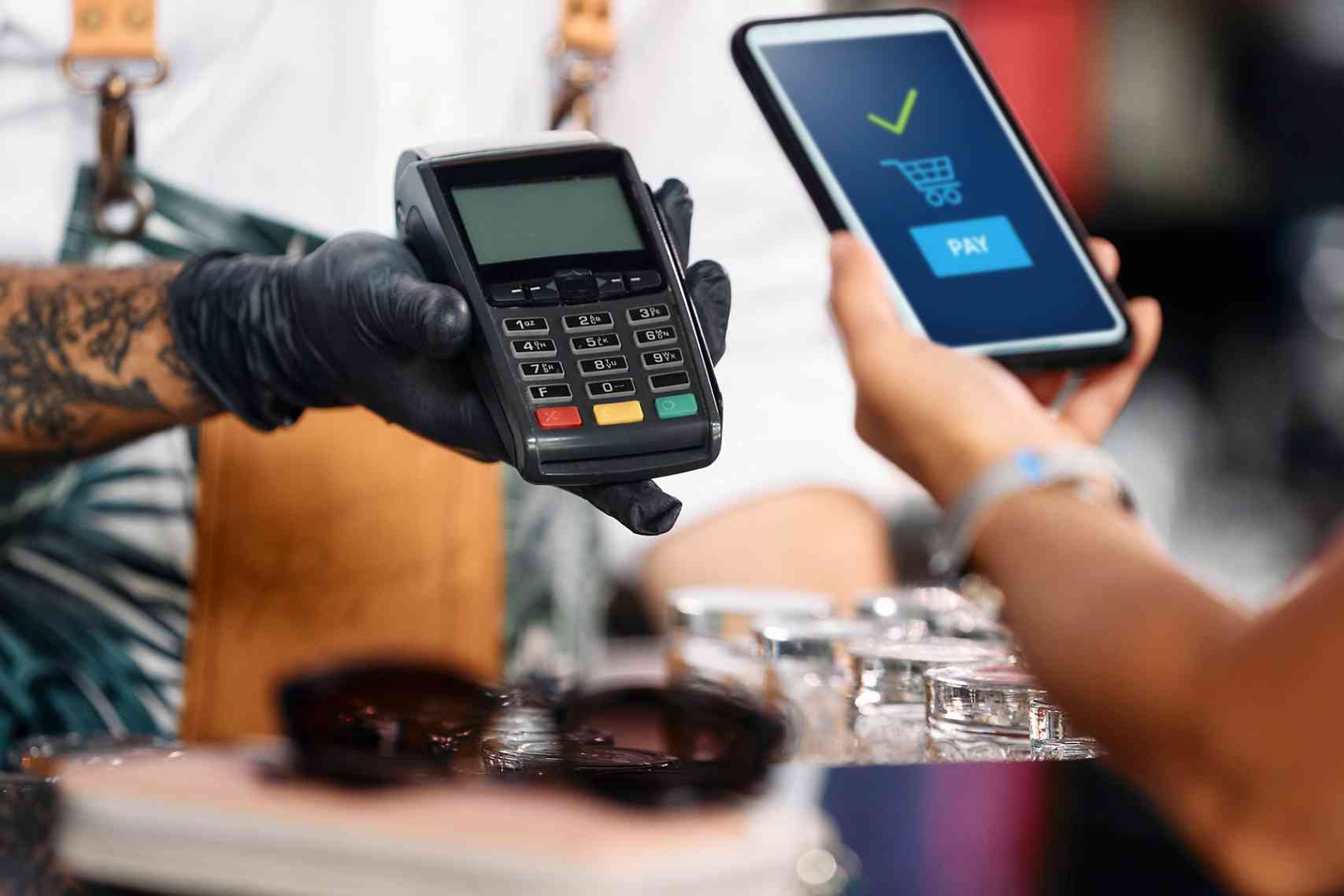 Close-up of woman makes contactless payment with smart phone in bar.