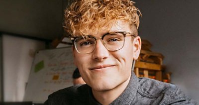 Curly hair blondy guy earing lasses smiling 