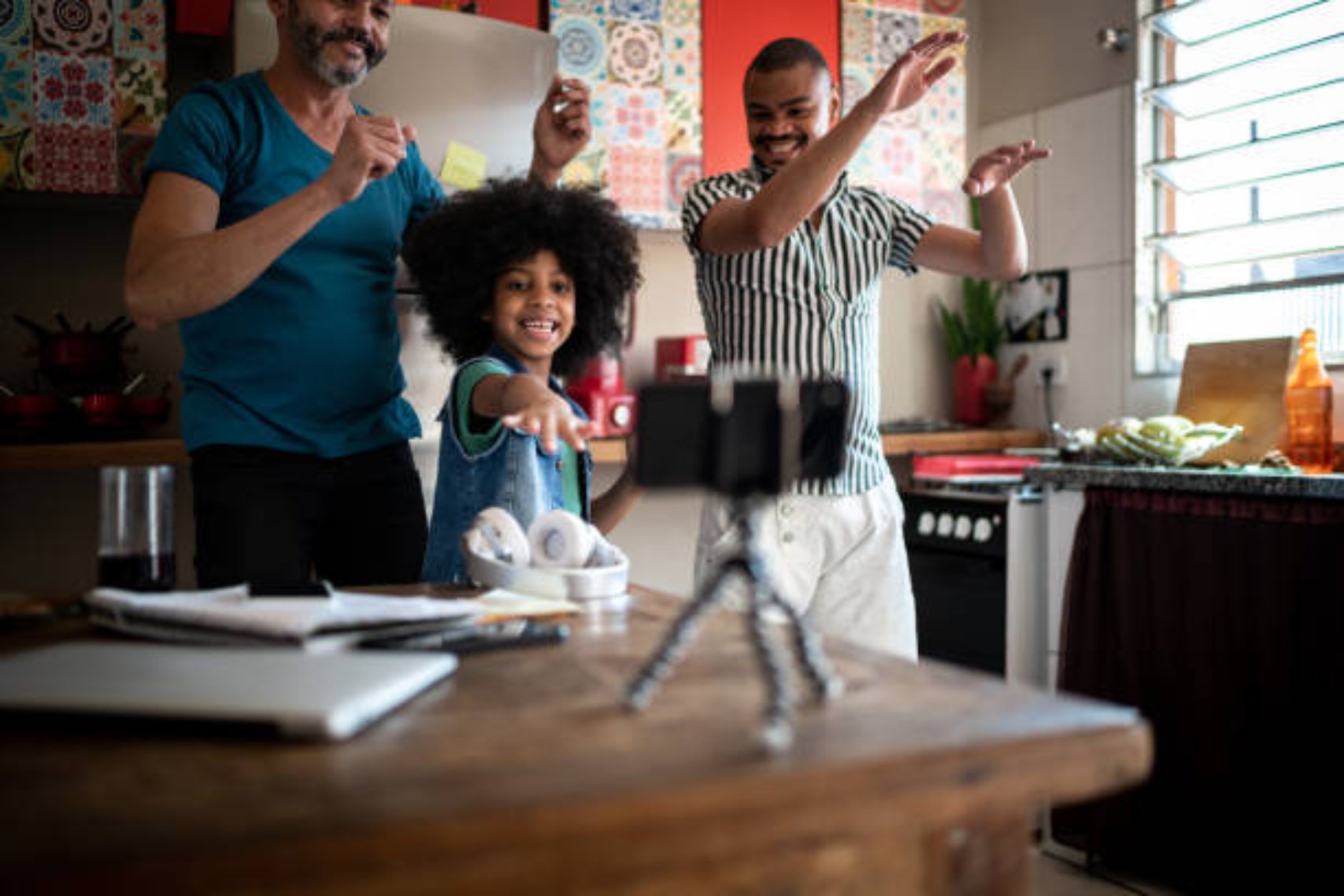 Family dancing at home, using smartphone on a tripod to film