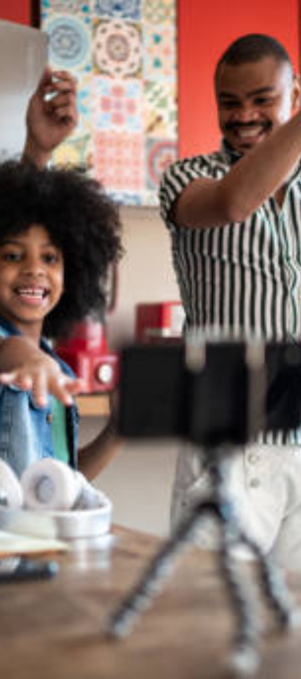 Family dancing at home, using smartphone on a tripod to film