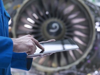 Hand holding a tablet device with turbine at the background