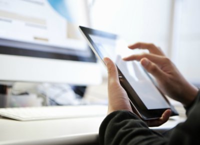 A man using an ipad and imac