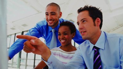 Three people smiling while looking at a computer