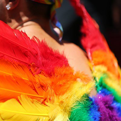A man wear Сupid's wings colored as a gay rainbow flag during New York Pride Parade.