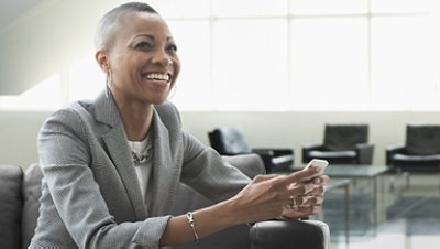 Woman smiling holding her phone wearing gray checkered blazer