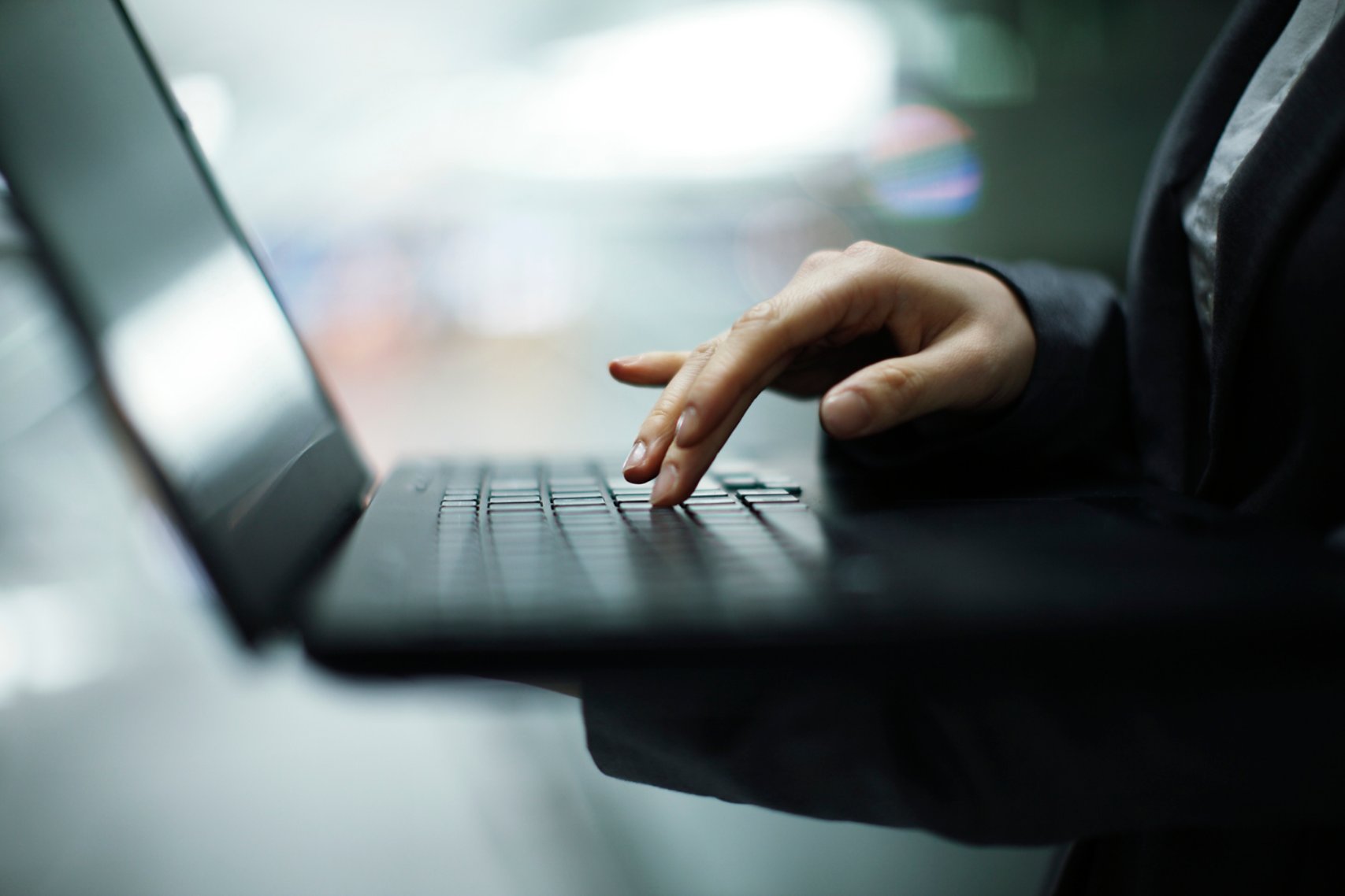 Una mano che tiene e usa un computer portatile