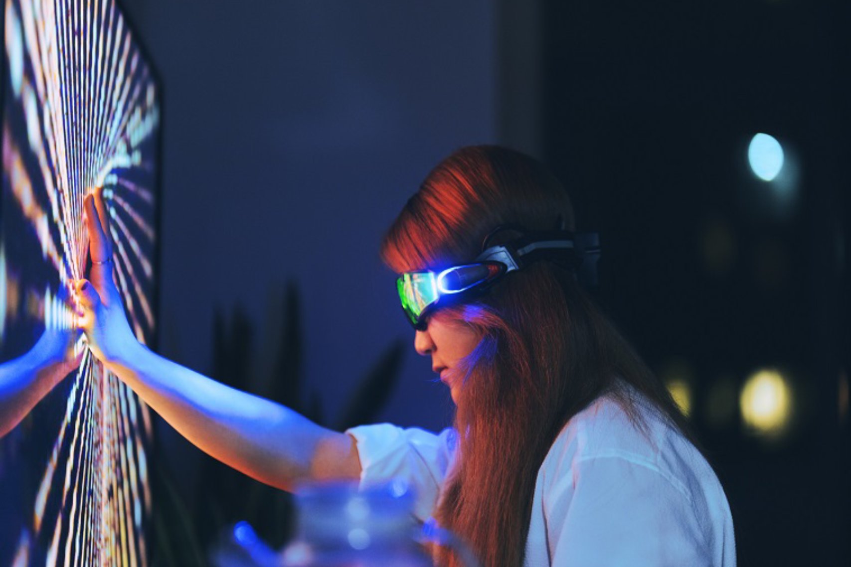 Young woman wearing augmented reality glasses touching screen with hands