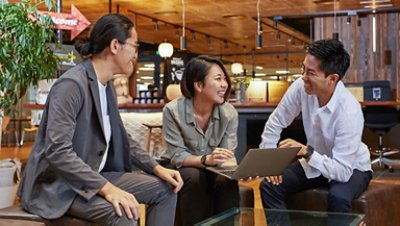 Two men and a woman laughing in a cafeteria