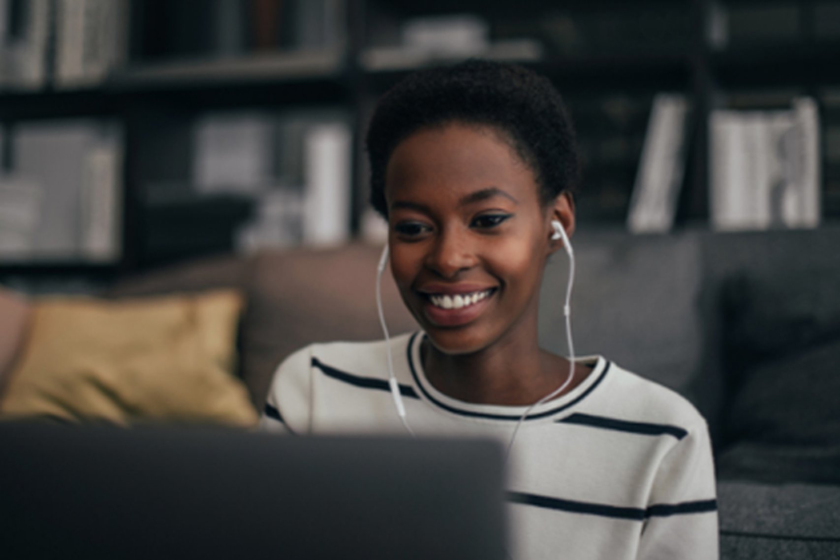 An image of a woman smiling while wearing an earphone