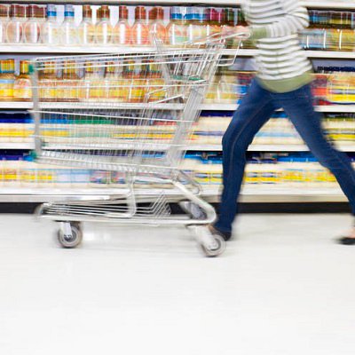 Woman Moving Quickly Down Grocery Aisle with Cart