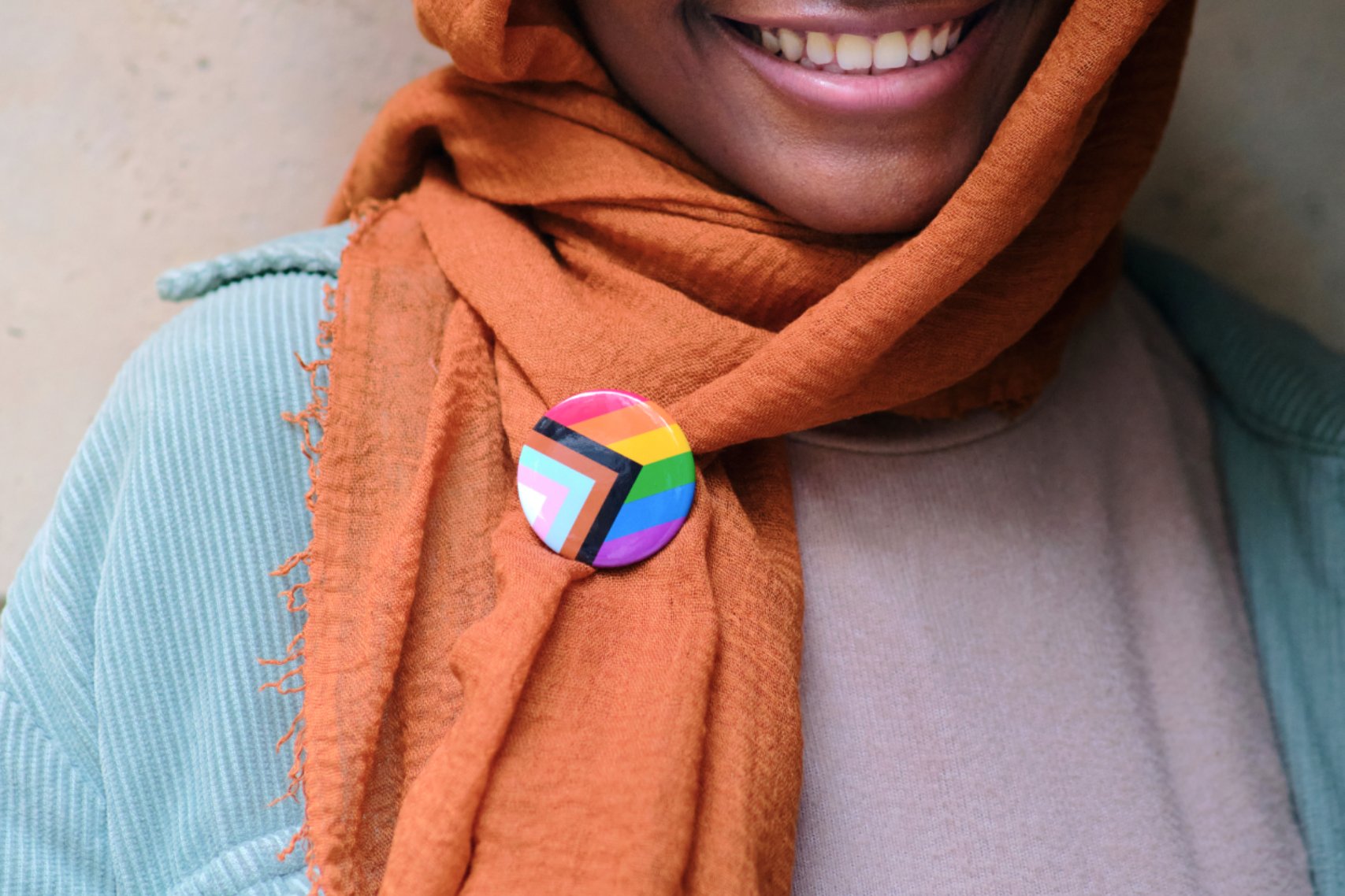 Smiling woman with LGBTIQA+ pin