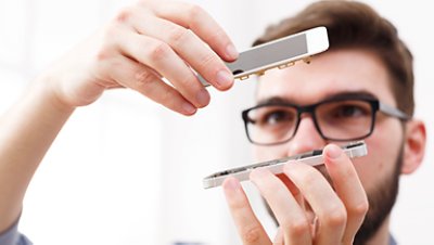 A man holding a disassembled mobile phone and looking at it