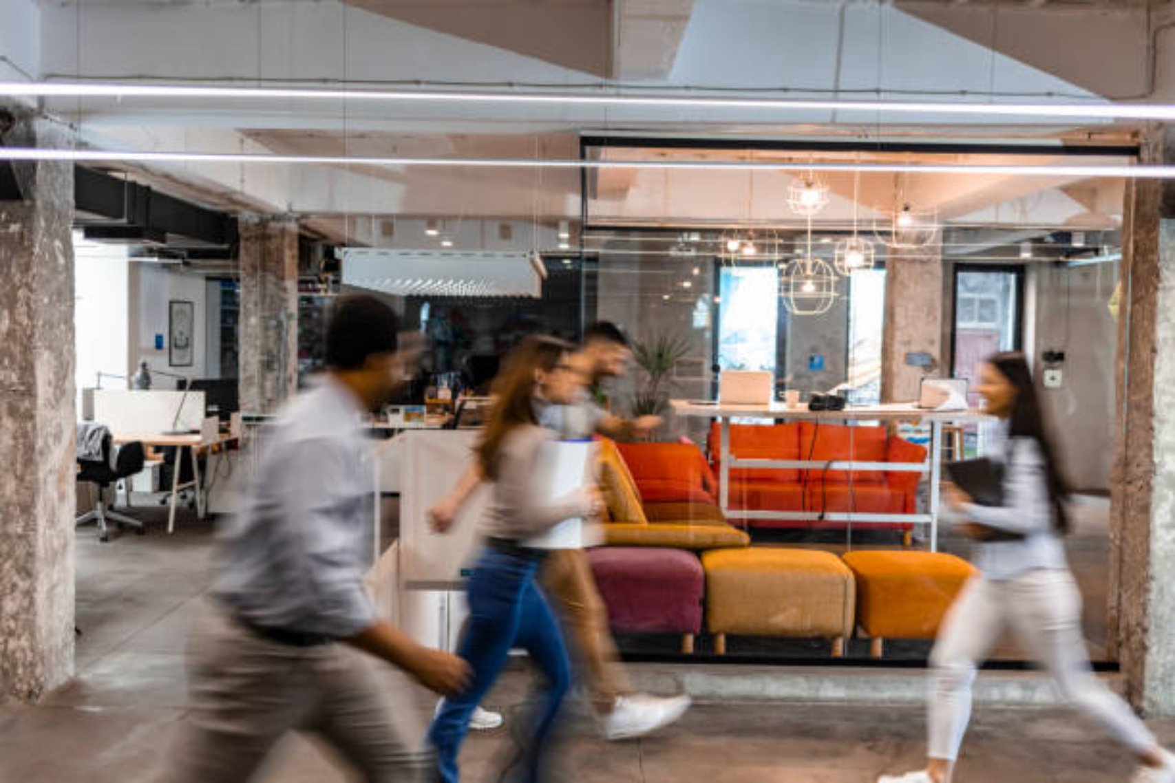 Several business people walking in the corridor. Four Business people walking at modern office. Group of business employees at co working centre. Motion blur. Concept work process. Wide image