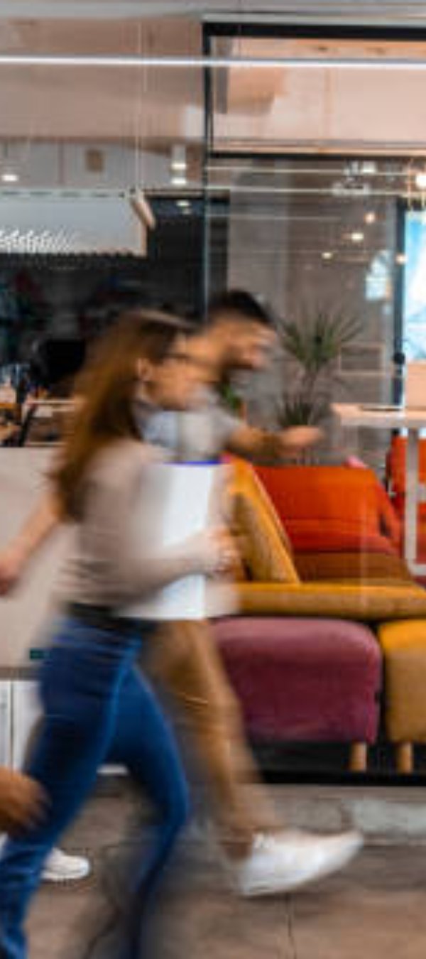 Several business people walking in the corridor. Four Business people walking at modern office. Group of business employees at co working centre. Motion blur. Concept work process. Wide image