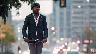 A guy in a corporate attire riding on his electric scooter 