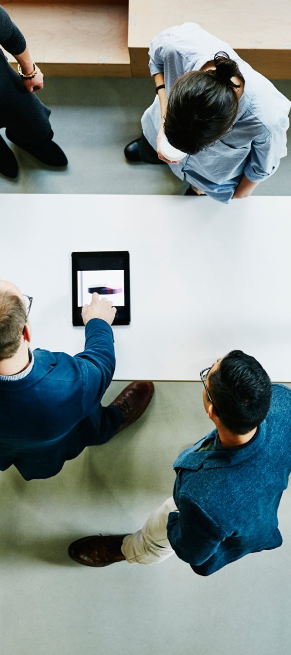 Overhead view of business colleagues discussing project on digital tablet