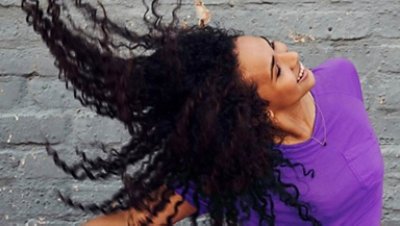 Women in a purple shirt flexing her long curly hair