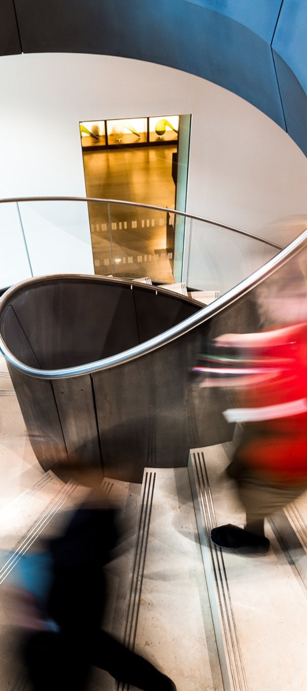 High angle image depicting an abstract view of a group of people running down a modern spiral staircase in the city.