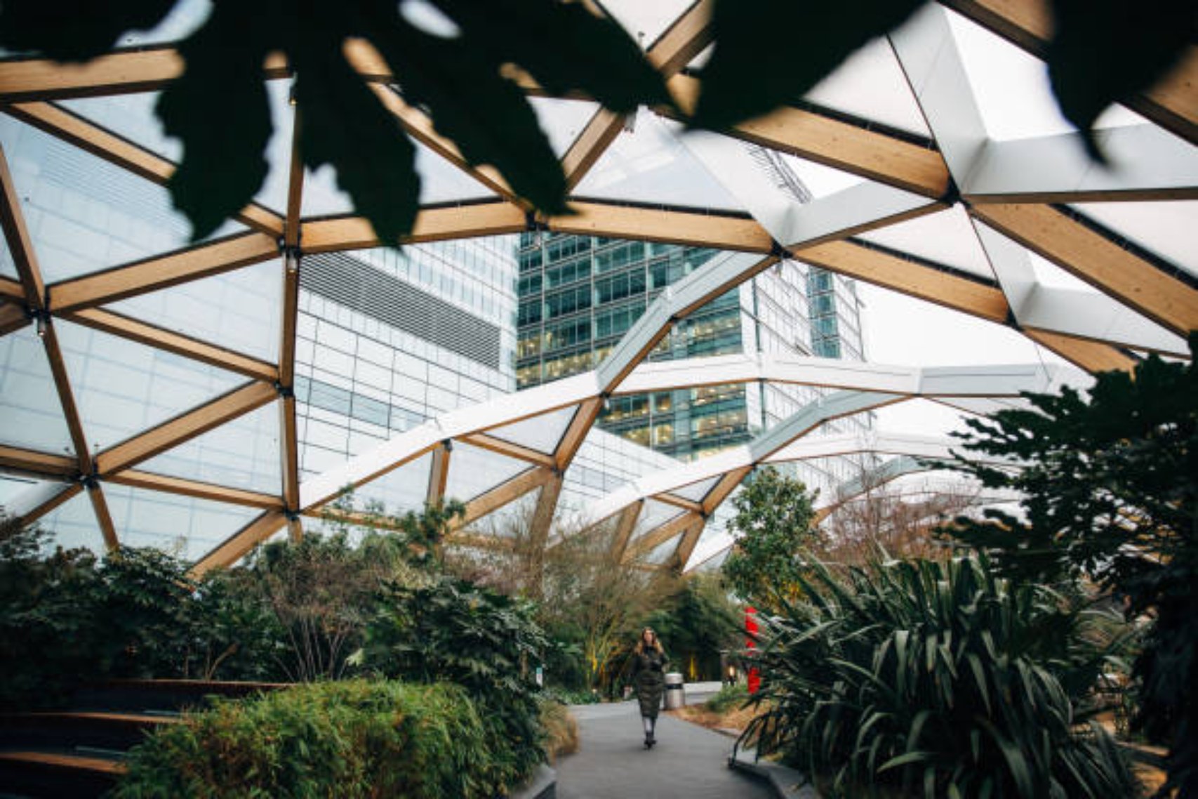 Woman in winter coat walking in hidden location at Canary Wharf, roof garden at Crossrail Place