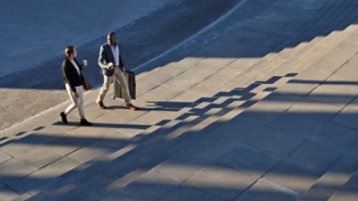 Two people holding a cup of coffee while walking in the street