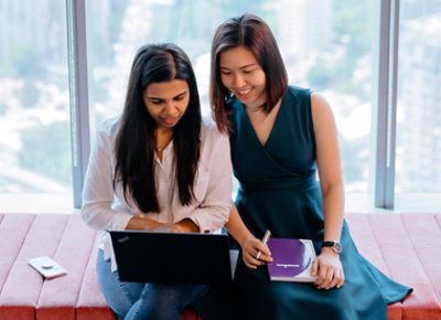 Two girls collaborating in work and taking notes