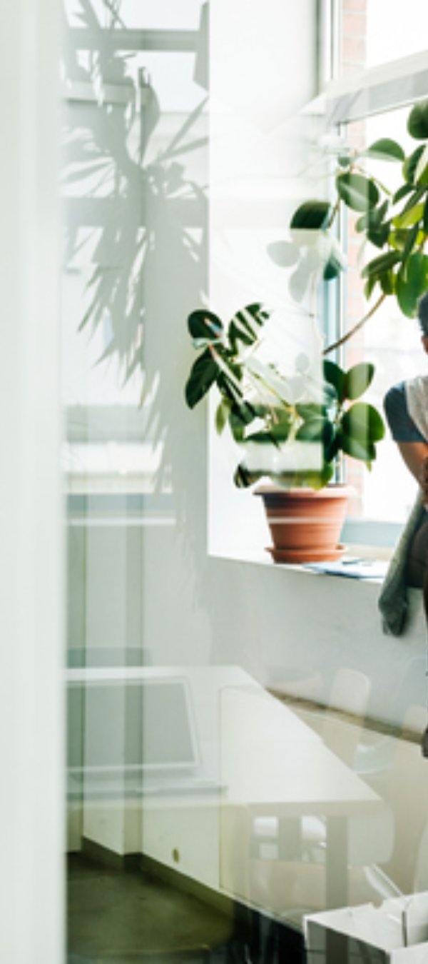 Two young start up business people sitting in a huge office window and talking.