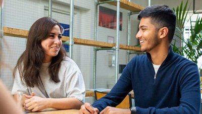 Man and woman are smiling sitting at a table indoors