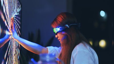 A women wearing VR headset and hand pressed against a digital screen