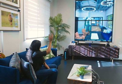 Image of a woman waving her hand while sitting on a couch