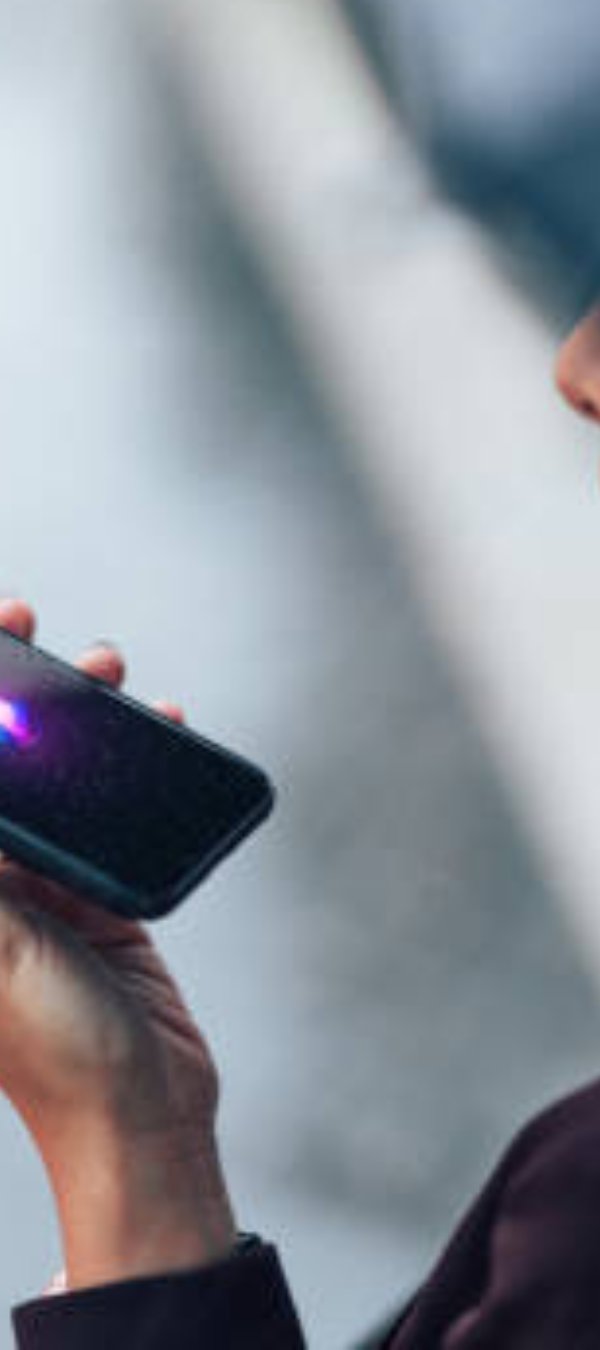 Close up shot of young Asian businesswoman talking to virtual assistant on smartphone in the rain.