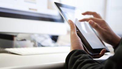 Hands on tablet in front of computer monitor