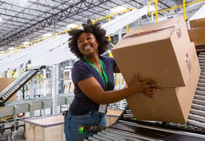 Woman worker holding boxes in factory.