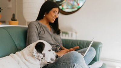 Image of a woman working on a laptop with her pet by her side