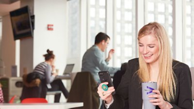 Women smiling looking ate her phone holding thumbler with accenture logo