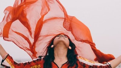 A woman wearing red clothing and is likely dancing or posing