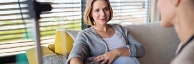 A pregnant woman visited by her doctor in her home.