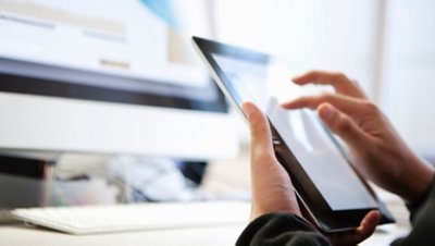 Person working on a tab with a monitor behind