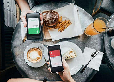 Photograph of a table with food showing a bill being split digitally on their smartphones.