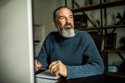 Portrait of senior man at desktop computer in home office