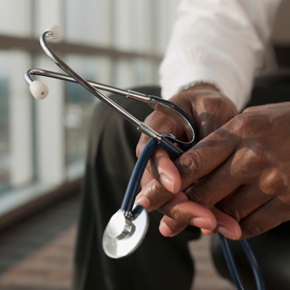 Médico sosteniendo el estetoscopio con ambas manos