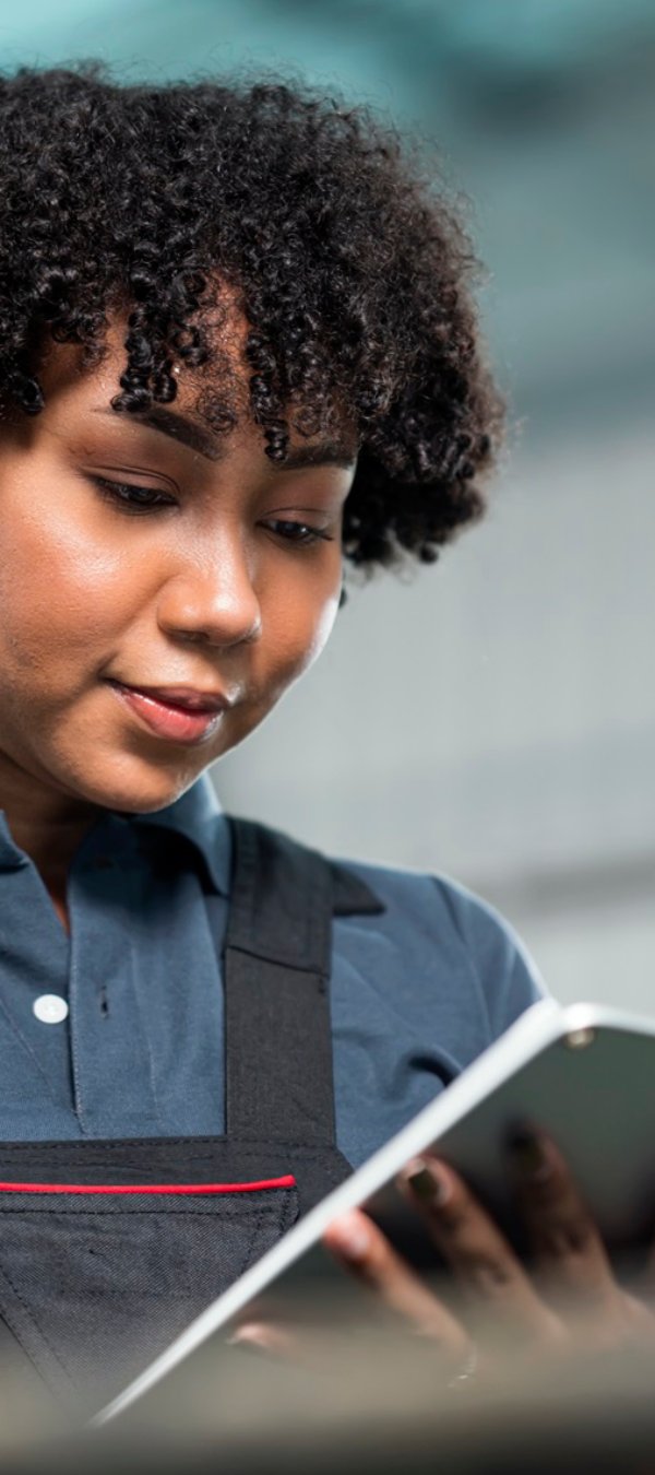 Quality Control in the Manufacturing Process. Female African American Quality Control Engineer is examining engineering workpiece by random visual check based on a quality standard check-sheet.