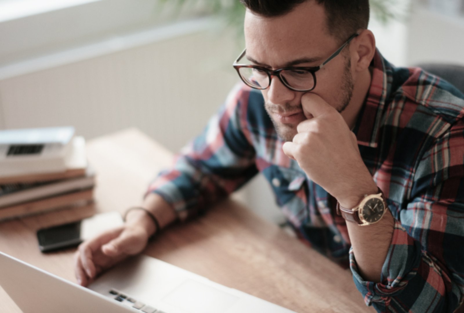 Man looking at his laptop while hands on chin